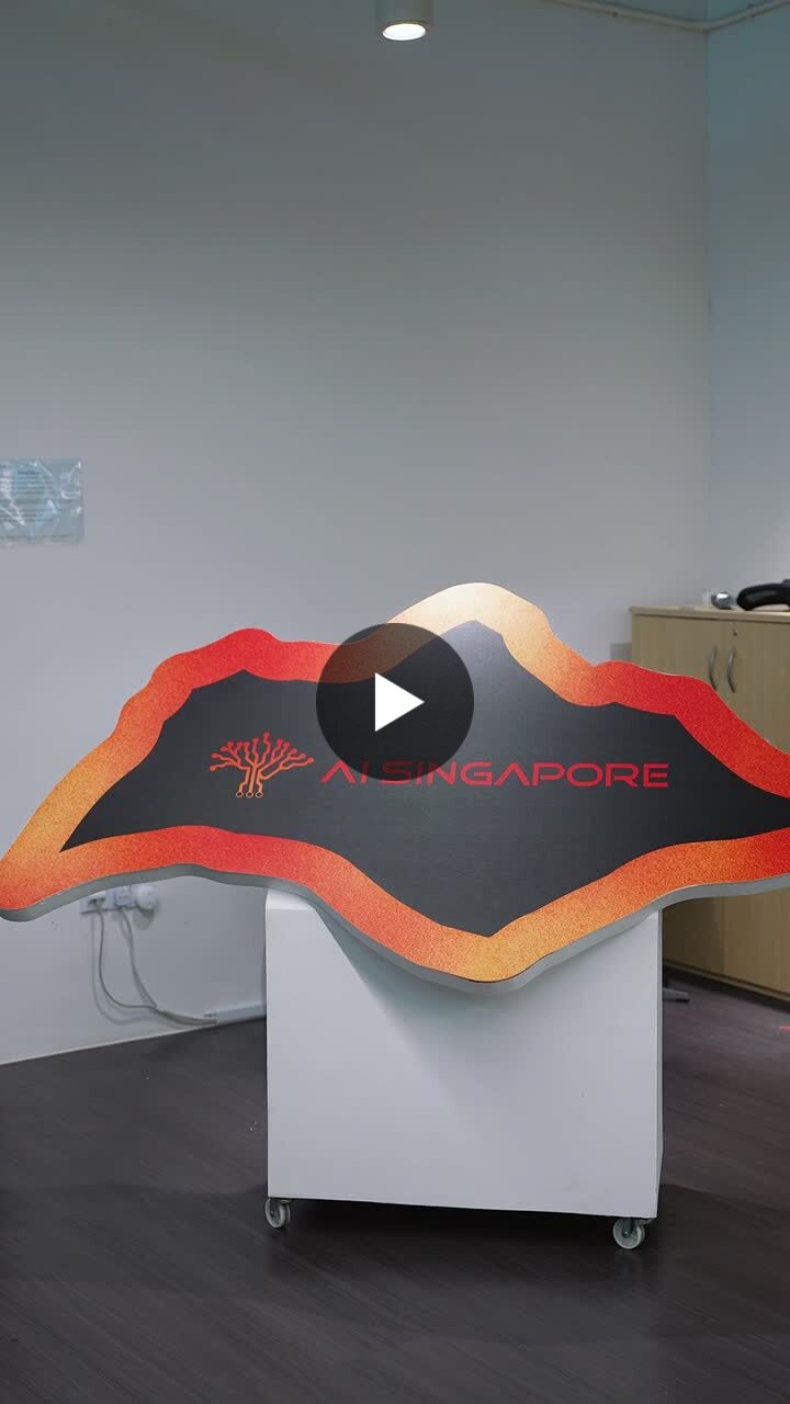 Opening frame of the film: the AI Singapore office reception, a wave-shaped desk carrying the orange AI Singapore wordmark.